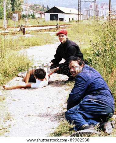 SARAJEVO, BOSNIA - JUNE 17: Two men duck for cover while trying to help another man critically injured by a sniper\'s bullet in a train yard in Sarajevo, Bosnia, on Thursday, June 17, 1993.