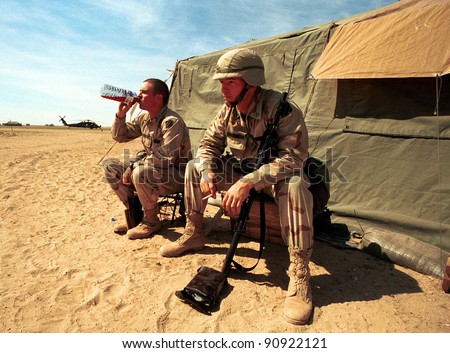 KUWAIT-IRAQ BORDER - FEBRUARY 22: Two United States Army soldiers enjoy a bit of a rest between military exercises just south of the Iraqi border in Kuwait  on Feb 22, 1998 on the Kuwait-Iraq border.
