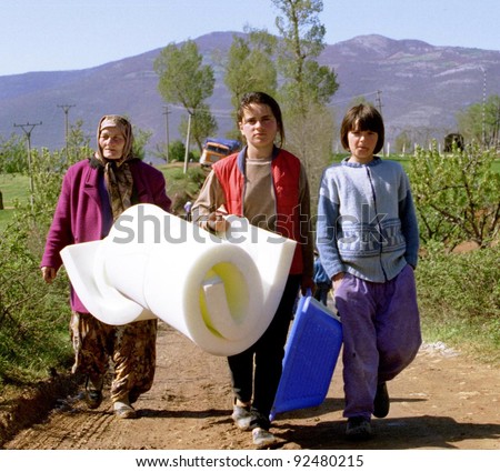 KUKES, ALBANIA - APRIL 17: A grandmother and her two granddaughters walk to their tent at a refugee camp along the Kosovo border after receiving a mattress from an international relief agency  on April 17, 1999 in Kukes, Albania