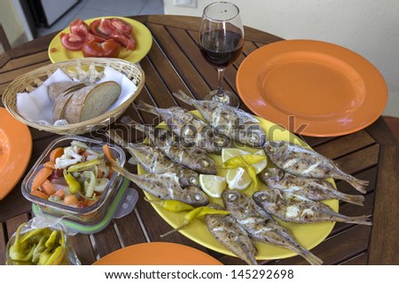 Barbecue fresh fishes with lemon, bread, tomatoes, wine and marinated vegetable