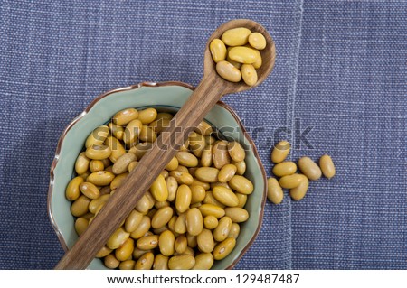 cup of beans with a wooden spoon on a light blue towel background