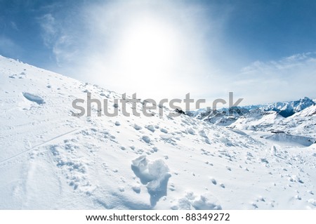 winter mountain scenery, fresh snow in foreground. cute mountain cabin buried in snow