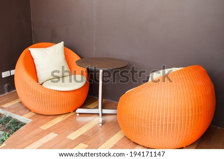 Orange outdoor wicker chairs with cushions.