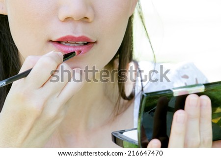 Cute Asian girl making up the lips.