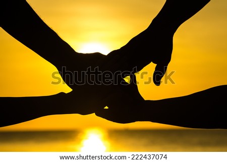 Hands uniting on sunset background at beachside