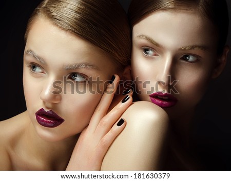 two beautiful young girls of model with naked shoulders, as from the magazine, with a beautiful make-up and bright lips on a black background