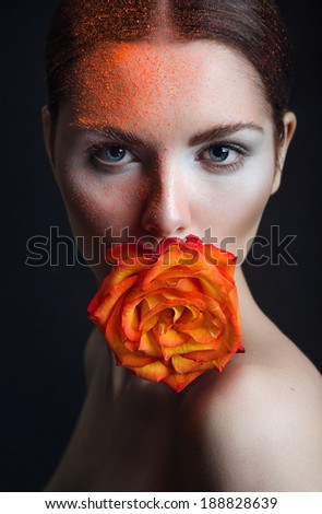 the beautiful girl model with shining skin with a saturated bright make-up in flowers, fiery color