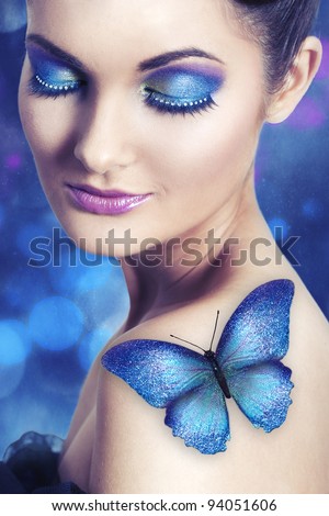 Young woman with blue make up and glitter butterfly on her shoulder