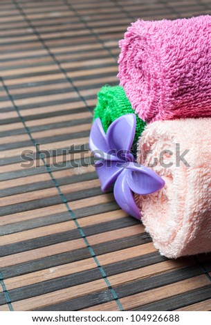 Spa towels rolls and flower lying on wooden mat. Space for your text. Vertical composition.