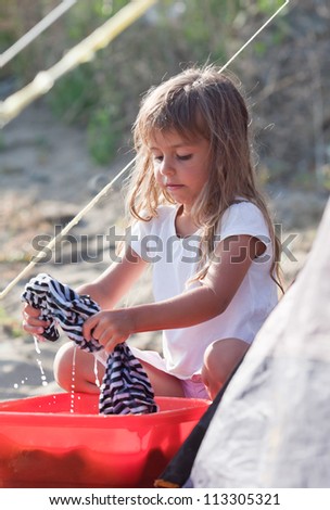 Little girl washes clothes with her hands