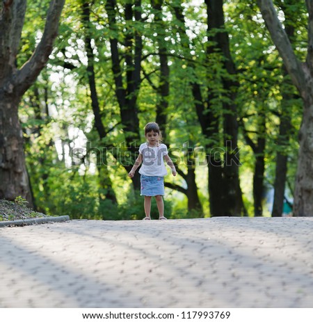 Little girl stands on the path in the park