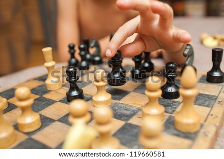 Chess game in action. Board in details. Close up of a child\'s hand playing chess