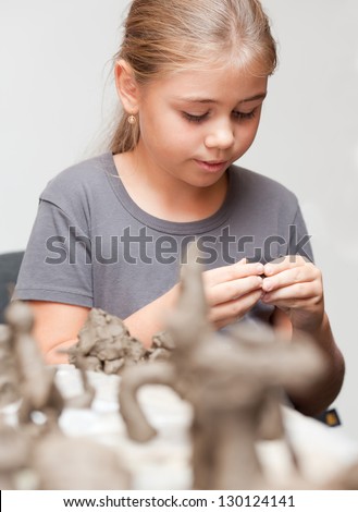 Little girl sculpts toy from clay with enthusiasm