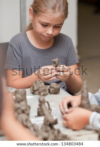 Little girl sculpts a toy from clay with enthusiasm
