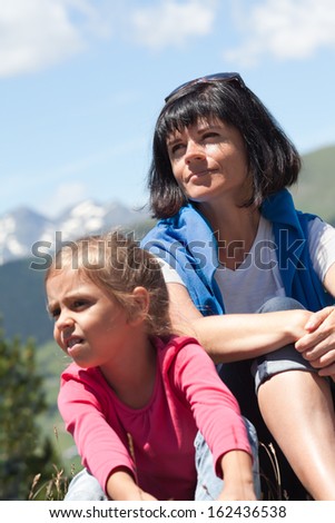 Portrait of a mother with her daughter outdoors the summer with snow covered mountains in the background