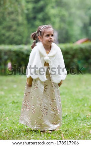 A beautiful little girl looks away, in a park