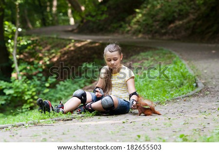 Cute little girl with roller blade and squirrel at park