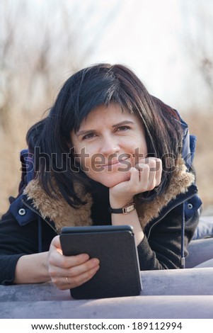 Woman portrait with tablet e-reader outdoors in forest camp
