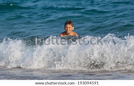 Happy boy swimming in a waves in the sea