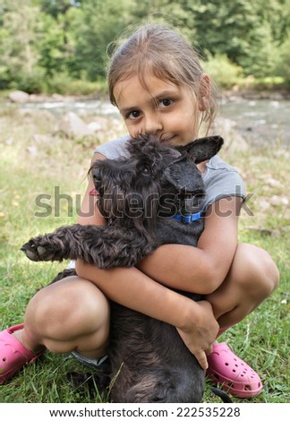 Smiling little girl hugging her lovely dog, resting together outdoors