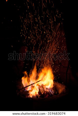 Air forced through a blacksmith forge stirs up a rain of sparks