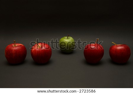 A line of apples, with one red one out.