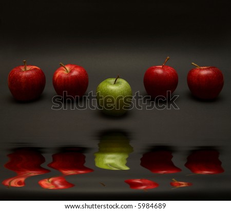 A line of apples with one exception. (with water reflection)