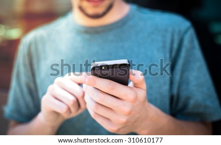 Man using smartphone mobile mobile device - focus on top of the phone
