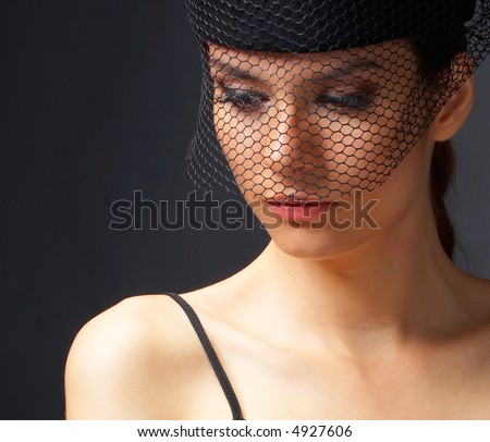 A closeup of a woman\'s face in black and white. She is wearing a vintage hat with a net