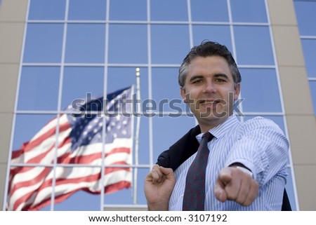 Businessman standing outside the office building with the American flag reflection in the windows