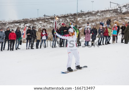 Novosibirsk, Russia - December 7, 2013 : young man snowboarding with the Olympic torch for the Olympic torch relay in Novosibirsk