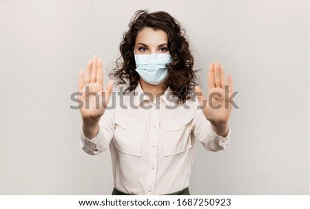 Masked woman makes stopping hand gesture. Influencer Girl blogger in medical mask talks about covid-19, coronavirus. Girl in medical mask stops 2019-nCov Stock fotó © 