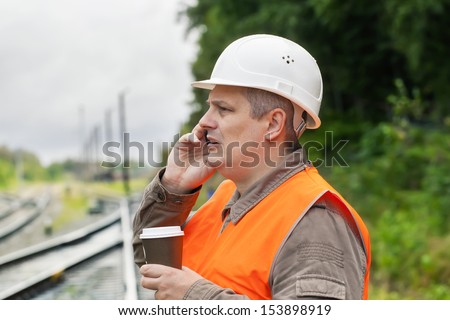 Worker with a coffee and cell phone on the railway