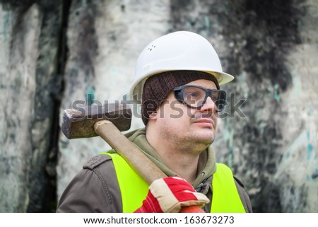 Man with sledge-hammer near old wall