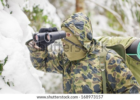 Hunter with binoculars in forest in the winter