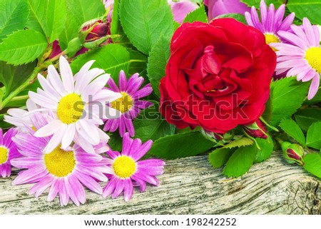 Rose with a variety of flowers on wooden board