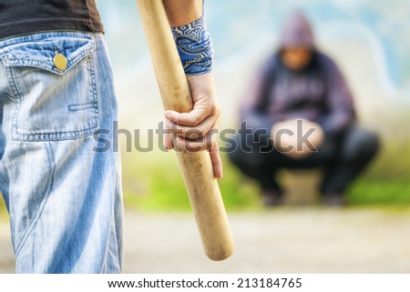 Aggressive man with a baseball bat against other man