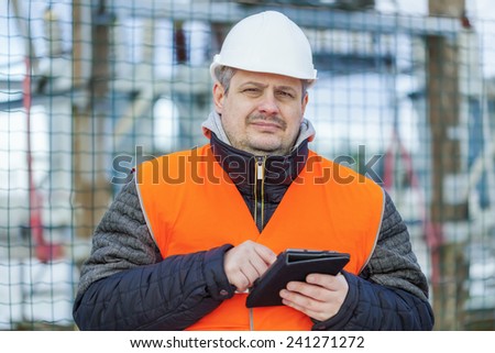 Electrical Engineer with tablet PC near the electric substation