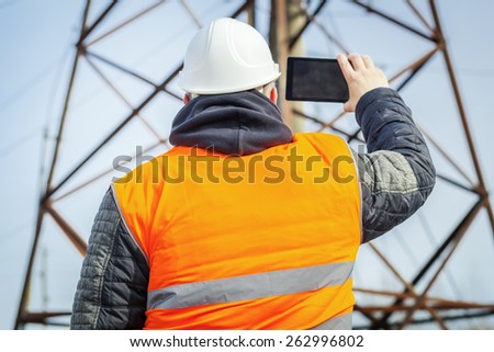 Electrical engineer filmed with tablet PC high voltage tower