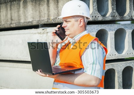 Construction Engineer using smartphone and laptop