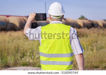 Railway Engineer filmed with tablet PC near freight wagons