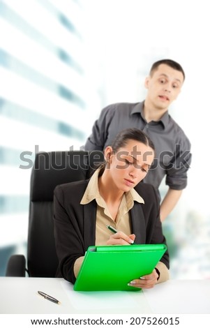 Businesswoman is hard working while her colleague looking furtively what she is writing.