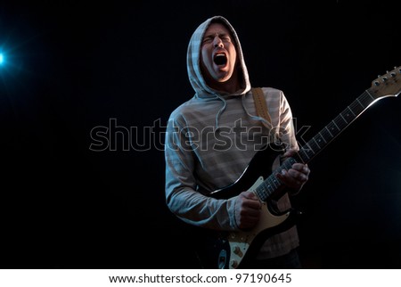 singing man wearing hooded sweatshirt ,  playing guitar on a black background,