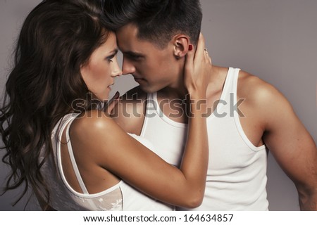 Beautiful young smiling couple in love embracing indoor