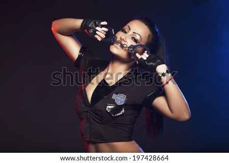 Sexy woman with police uniform in studio on dark red and blue background