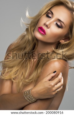 Young sexy blond woman without lingerie with pink lips posing on studio