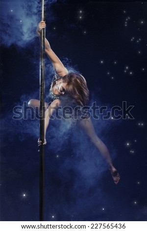 Young sexy woman pole dancer. Smoke and stars studio photo