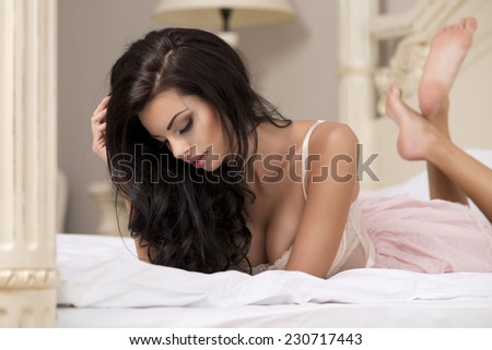 Beauty brunette woman in stylish room, wearing pink costume, ballet skirt and corset lying on bed