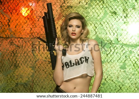 portrait of sexy blonde  with gun against camouflage net