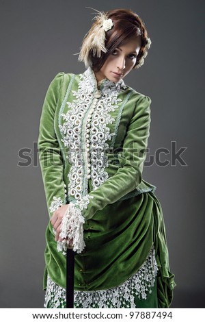 Delicate brunette with walking stick  posing in a vintage dress